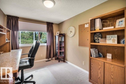 Room featuring a large window, carpet flooring, a ceiling-mounted light fixture, and built-in shelving with lower cabinetry - 11742 29 Avenue, Edmonton, AB 