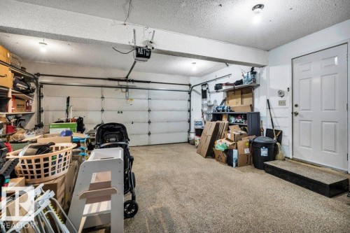 Two-car garage featuring segmented garage doors, exposed ceiling beams, an interior access door, and overhead lighting - 11742 29 Avenue, Edmonton, AB 