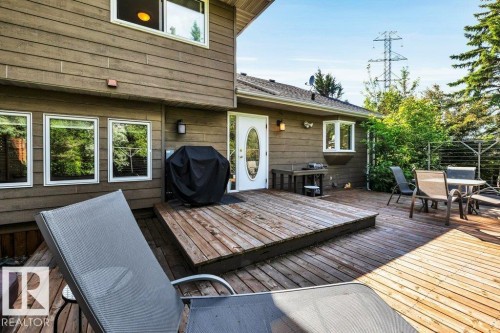 Expansive multi-level wood deck featuring a step-up platform, white frame windows, a bay window, and a white paneled door with an oval glass insert - 11742 29 Avenue, Edmonton, AB 