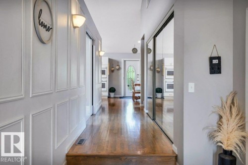Hardwood flooring entry with wainscoting wall paneling, wall sconces, mirrored sliding closet doors, and recessed lighting - 11742 29 Avenue, Edmonton, AB 
