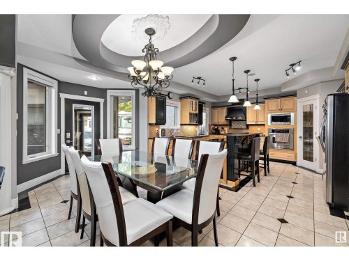 Dining area featuring a decorative ceiling medallion, an ornate chandelier, and tile flooring with accent squares - 9544 154 Street, Edmonton, AB 