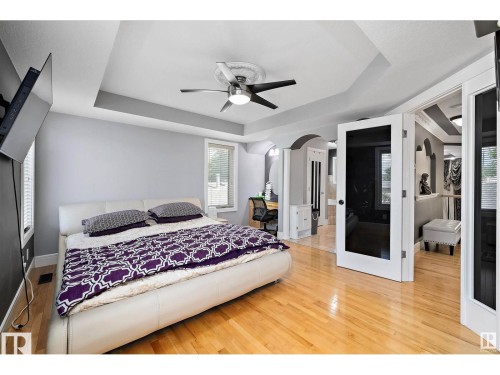 Bedroom featuring wood-finish flooring and a tray ceiling with a ceiling fan - 9544 154 Street, Edmonton, AB 