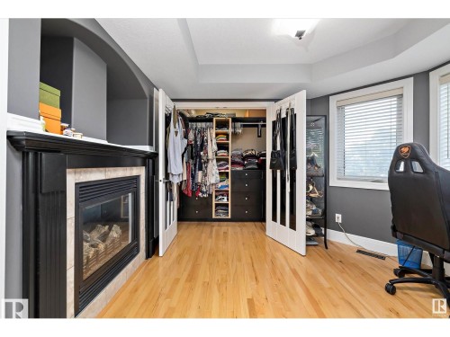 Hardwood flooring throughout the room, featuring a built-in fireplace with a tiled surround and black mantel - 9544 154 Street, Edmonton, AB 
