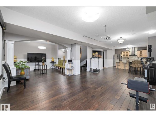 Spacious lower-level area featuring dark wood-finish flooring, white wainscoting, arched architectural details, and recessed lighting - 9544 154 Street, Edmonton, AB 