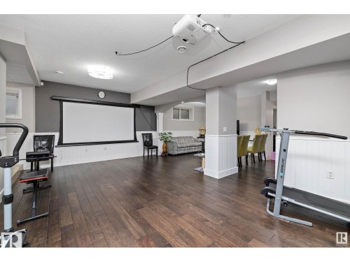 Open concept recreational space featuring dark wood-finish flooring and white wainscoting - 9544 154 Street, Edmonton, AB 
