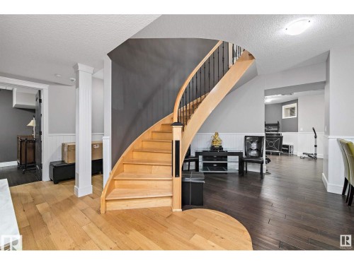 Curved staircase featuring natural wood treads and black metal balusters - 9544 154 Street, Edmonton, AB 