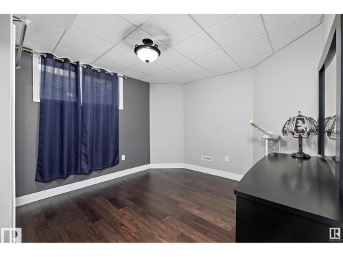 Room featuring dark wood-finish flooring, white baseboards, and a neutral wall color with a contrasting accent wall - 9544 154 Street, Edmonton, AB 