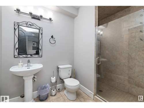 Pedestal sink with chrome faucet, complemented by a decorative framed mirror - 9544 154 Street, Edmonton, AB 
