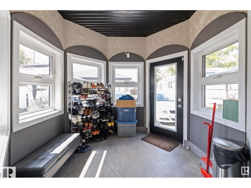 Enclosed entryway featuring multiple windows, a full-light entry door, a built-in bench, and plank flooring - 9544 154 Street, Edmonton, AB 