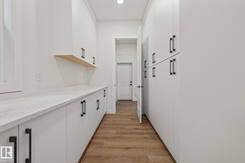 White cabinetry with black pulls, light wood-finish flooring, white countertops, built-in shelving, and recessed lighting - 132 Edgewater Circle, Leduc, AB 
