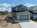 Contemporary residential exterior featuring a two-car garage, concrete driveway, and stone veneer accents - 132 Edgewater Circle, Leduc, AB 