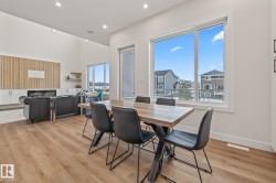 Open-concept dining and living area featuring wood-finish flooring, recessed lighting, and large windows - 