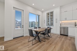 Spacious dining area featuring wood-finish flooring, a full-lite exterior door, and a large window - 
