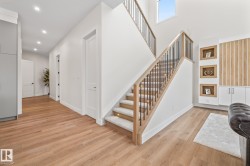 Staircase with wood handrail, black balusters, and carpeted treads featuring integrated lighting - 