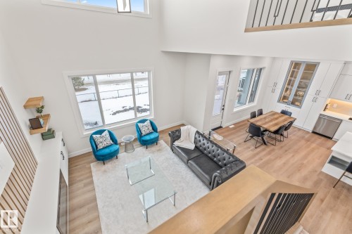 Two-story living area with high ceilings, wood-finish flooring, and large windows - 132 Edgewater Circle, Leduc, AB 