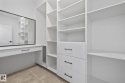 Spacious custom closet featuring extensive white shelving and built-in drawers with matte black hardware - 