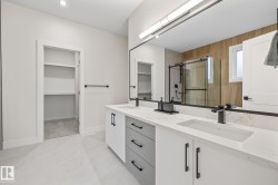 Contemporary bathroom featuring a double vanity with stone countertops, integrated sinks, and matte black fixtures - 