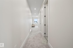 Bright hallway featuring light-toned carpet flooring, recessed lighting, and white walls - 