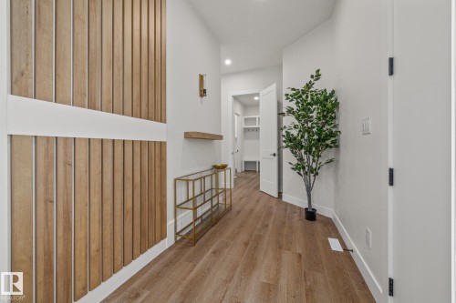 Entryway featuring wood-finish flooring and a vertical wood slat accent wall - 132 Edgewater Circle, Leduc, AB 