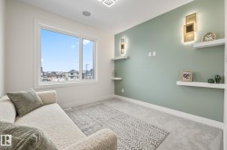 Bright room featuring a large picture window, soft gray carpeting, and a contrasting accent wall with built-in floating shelves and integrated sconce lighting - 