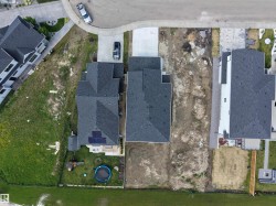 Newly constructed residential property featuring a dark shingled roof, attached concrete driveway, and solar panel installation - 
