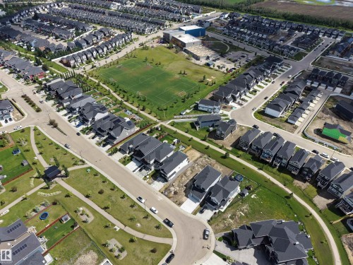Expansive aerial perspective showcasing a residential community with a large central park featuring a sports field - 132 Edgewater Circle, Leduc, AB 