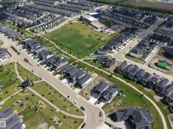 Expansive aerial perspective showcasing a residential community with a large central park featuring a sports field - 
