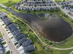 Aerial perspective showcasing a residential area bordered by a large pond with surrounding green spaces - 