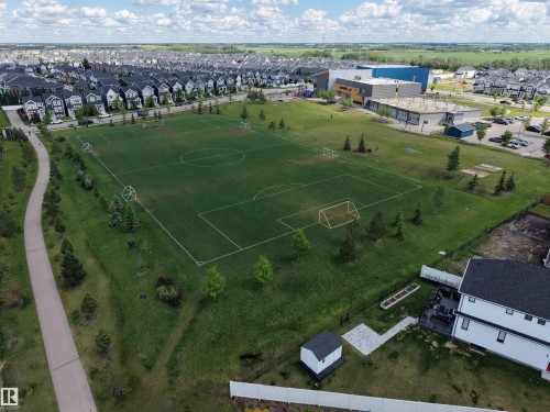 Expansive green space featuring a marked sports field, perimeter walking path, and surrounding residential development - 132 Edgewater Circle, Leduc, AB 