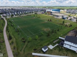 Expansive green space featuring a marked sports field, perimeter walking path, and surrounding residential development - 