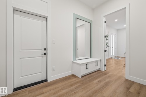 Entryway featuring wood-finish flooring, a built-in storage bench with a framed mirror, and recessed lighting - 132 Edgewater Circle, Leduc, AB 