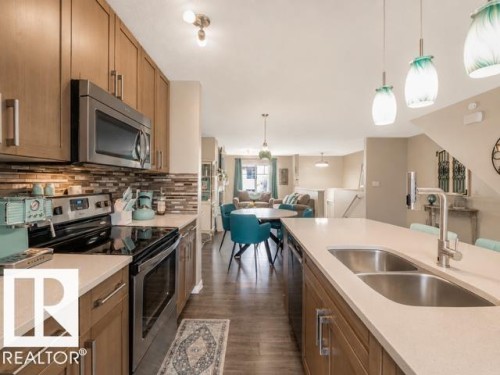 Kitchen featuring wood-finish cabinetry, stainless steel appliances, and a mosaic tile backsplash - 44 1140 Chappelle Boulevard, Edmonton, AB 