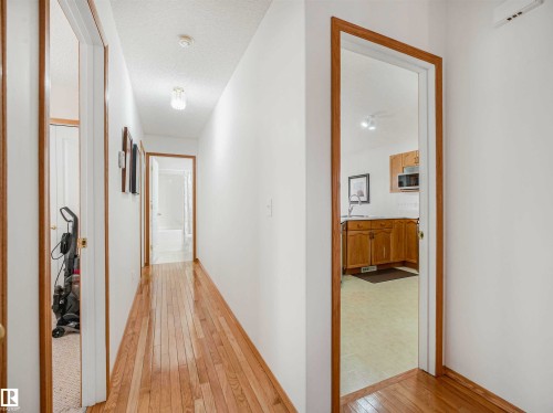 Hardwood-style flooring extends through a bright hallway with white walls and natural wood trim - 13825 128A Avenue, Edmonton, AB - Indoor Photo Showing Other Room