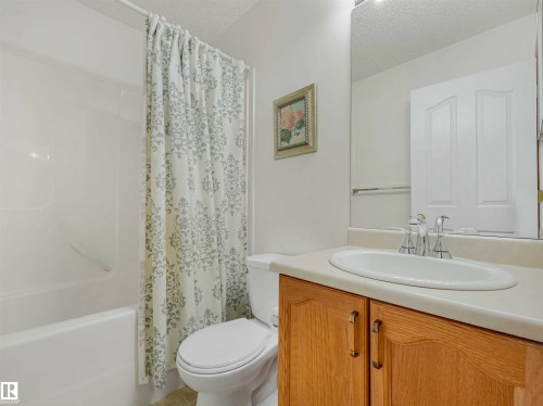 Bathroom featuring a built-in vanity with wood-finish cabinetry, a white oval sink, and a large wall-mounted mirror - 13825 128A Avenue, Edmonton, AB - Indoor Photo Showing Bathroom