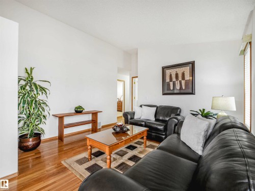Bright living area featuring wood-finish flooring, vaulted ceilings, and white wall finishes - 13825 128A Avenue, Edmonton, AB - Indoor Photo Showing Living Room