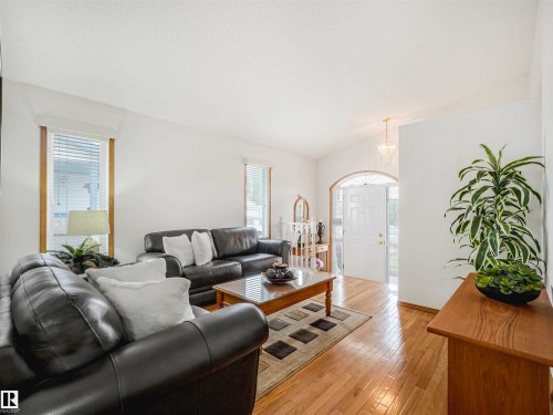 Living area featuring wood-finish flooring, white walls, and bright window treatments - 13825 128A Avenue, Edmonton, AB - Indoor Photo Showing Living Room