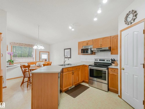 Kitchen featuring wood-finish cabinetry, stainless steel appliances, white countertops, and a white tile backsplash - 13825 128A Avenue, Edmonton, AB - Indoor Photo Showing Kitchen With Double Sink
