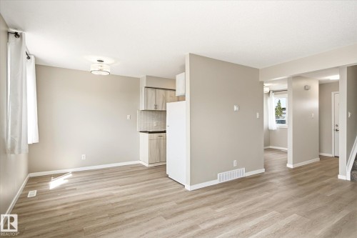 Open-concept living area featuring wood-finish flooring, neutral wall tones, and a modern semi-flush ceiling light fixture - 186 Cornell Crest, Edmonton, AB 
