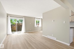 Spacious living area featuring light wood-finish flooring and neutral painted walls - 