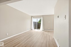 Spacious room featuring light wood-finish flooring, neutral wall tones, and a sliding glass door leading to an outdoor area - 