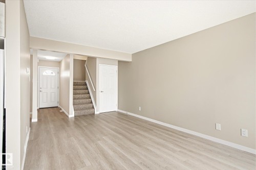 Open-concept living area featuring wood-finish flooring, neutral wall tones, and white trim - 186 Cornell Crest, Edmonton, AB 