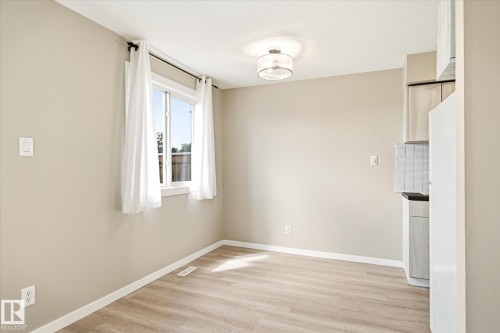 Bright room featuring light wood-finish flooring, a contemporary ceiling light fixture, and a window with white trim - 186 Cornell Crest, Edmonton, AB 