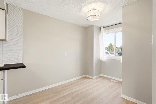 Naturally lit interior space featuring light wood-finish flooring, a contemporary semi-flush mount ceiling fixture, and a window with white trim - 186 Cornell Crest, Edmonton, AB 
