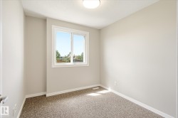 Room featuring a window with white trim, light gray walls, textured carpet, white baseboards, and a flush-mount ceiling light - 