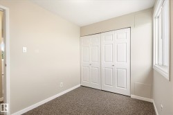 Neutral-toned room featuring a window, bi-fold closet doors, wall-to-wall carpeting, and white baseboards - 