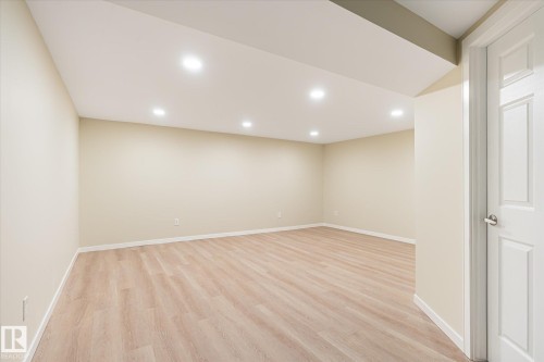 Spacious room featuring wood-finish flooring, recessed lighting, neutral wall tones, and white trim - 186 Cornell Crest, Edmonton, AB 