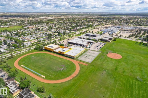 Expansive aerial view showcasing a large residential area with abundant green spaces, including a track and field, a baseball diamond, and multiple sports fields - 186 Cornell Crest, Edmonton, AB 