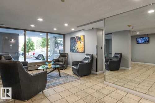 Lobby area featuring tiled flooring, recessed lighting, expansive window panels, full-height mirror panelling, and a mounted security display screen. - #602 12303 Jasper Av Nw, Edmonton, AB - Indoor