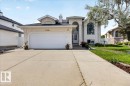 Stucco exterior residence featuring a prominent arched window, attached two-car garage, and a concrete driveway - 7936 165 Avenue, Edmonton, AB 