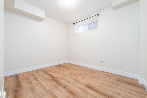 Bright room featuring wood-finish flooring, white baseboards, a window with a curtain rod, and neutral wall paint - 12246 103 Street, Edmonton, AB - Indoor Photo Showing Other Room
